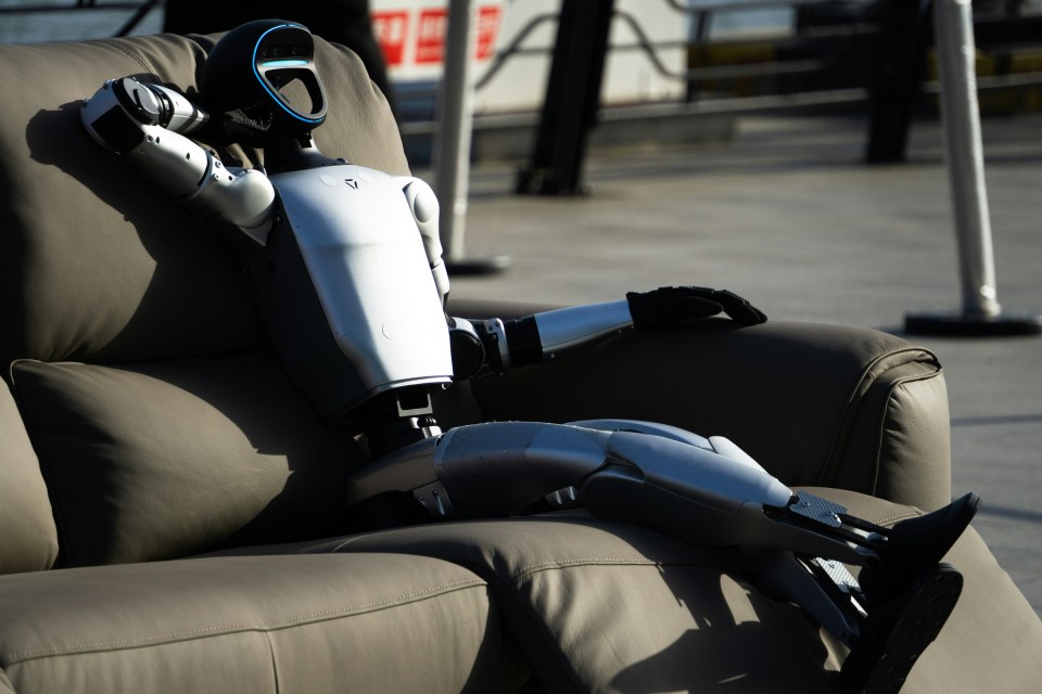 A photo of a human like robot relaxing on a sofa, clearly waiting for a human to catch-up.